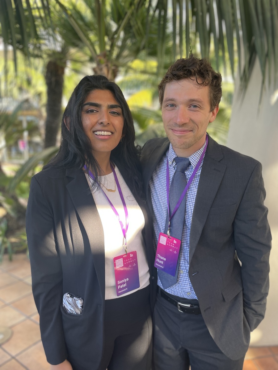a photo of a young Indian American woman and young white man standing together in front of palm trees at the Remarkable Tech Summit. 